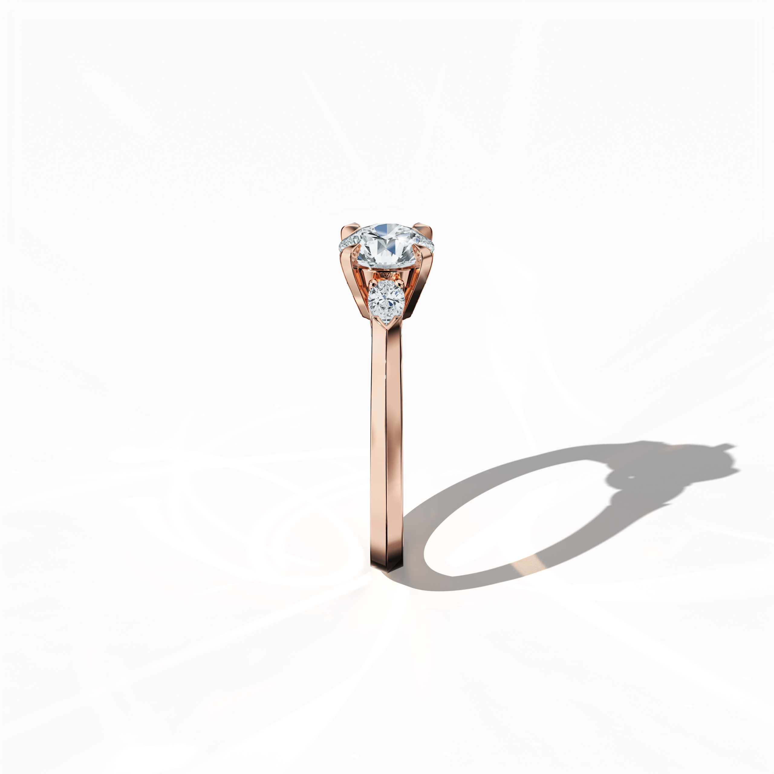 Side view of a rose gold trio diamond ring highlighting 1.30 ct natural diamonds—a 1 ct round center/centre diamond flanked by two pear‐shaped side diamonds (0.30 ct total) in a refined slim band with a four‐nail prong setting. This profile accentuates its graceful silhouette and warm radiance as an engagement ring, wedding band, or fine jewelry/fine jewellery piece. Also known as a trilogy ring, three‐stone ring, three‐diamond ring, trinity ring, and triptych ring design. Keywords: rose gold, trio diamond.