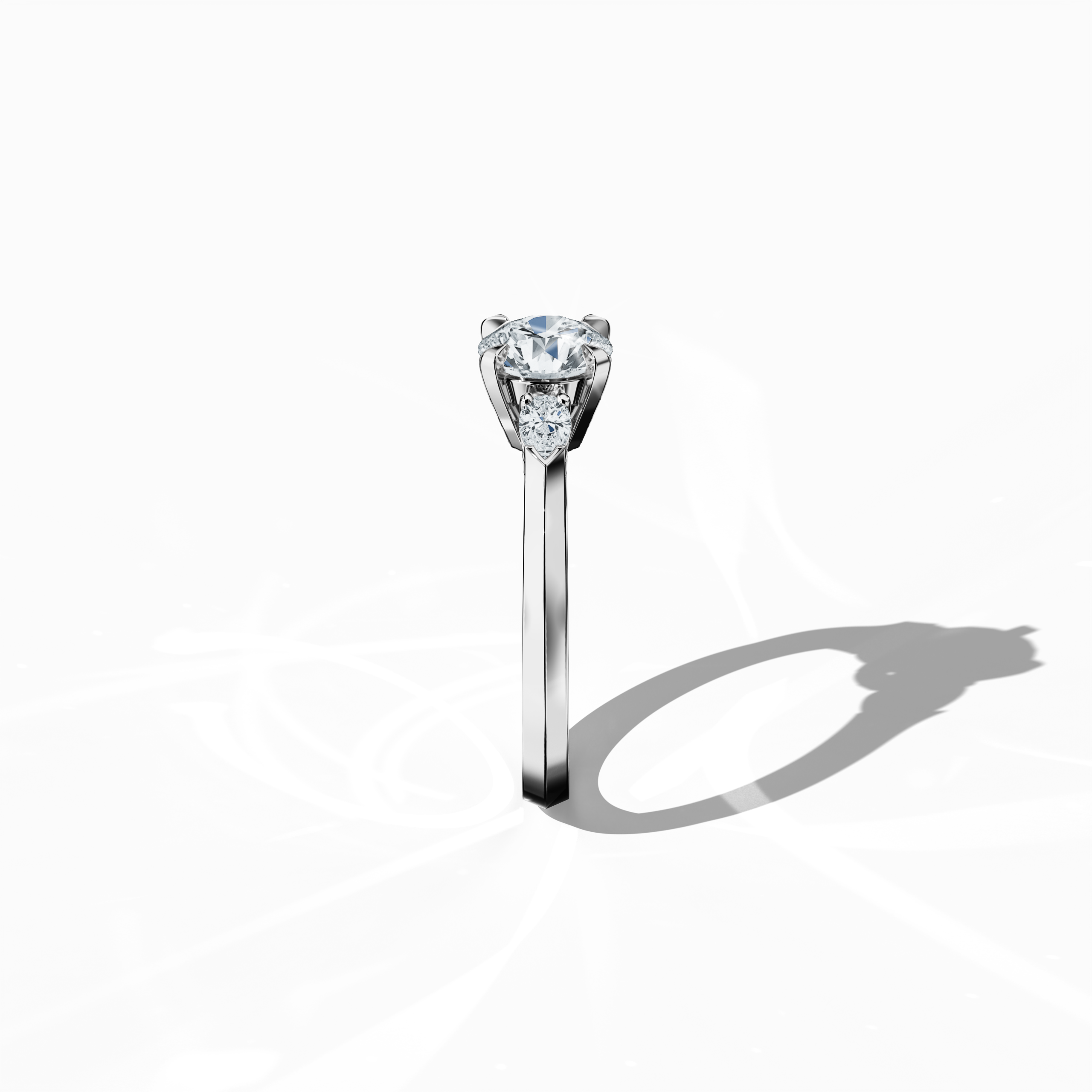 Side view of a white gold trio diamond ring, emphasizing a luminous 1 ct round center/centre diamond flanked by two pear‐shaped side diamonds (0.30 ct total) set in a refined slim band with a four‐nail prong setting. This angle accentuates its elegant profile and distinctive design, perfect for an engagement ring, wedding band, or fine jewelry/fine jewellery accessory. Also known as a trilogy ring, three‐stone ring, three‐diamond ring, trinity ring, and triptych ring design. Keywords: white gold, trio diamo