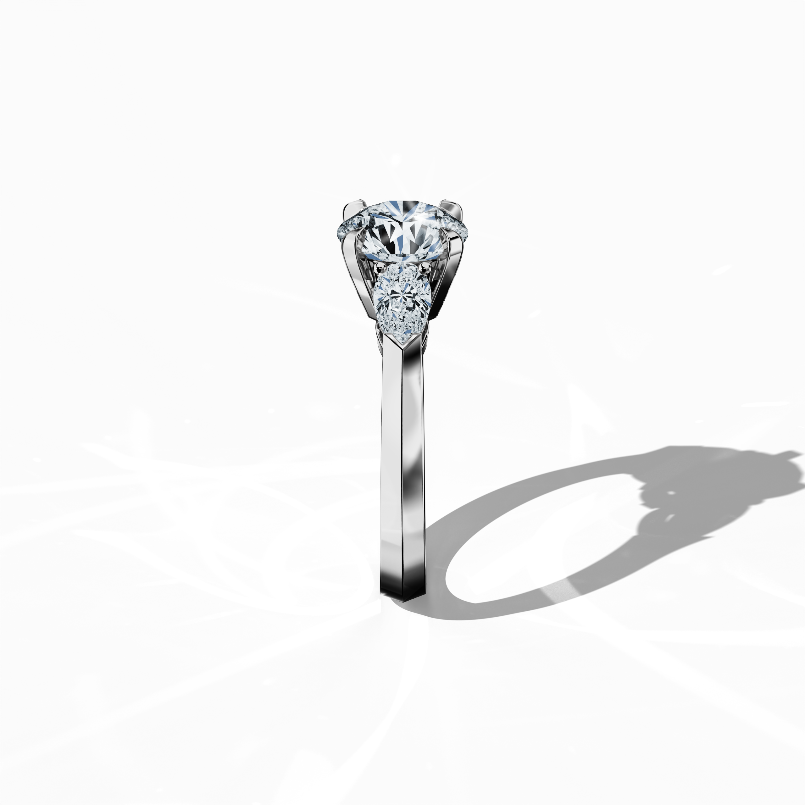 Side view of a white gold trilogy diamond ring highlighting 2.55 ct natural diamonds—a 2 ct round center/centre diamond flanked by two pear‐shaped side diamonds (0.55 ct total) in a refined slim band with a four‐nail prong setting. This perspective emphasizes its graceful silhouette and radiant brilliance, perfect as an engagement ring, wedding band, or fine jewelry/fine jewellery accessory. Also known as a trilogy ring, three‐stone ring, three‐diamond ring, trinity ring, and triptych ring design.